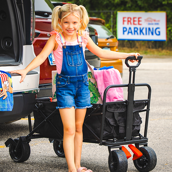 A young girl stands next to her car with a sign advertising Free Parking behind her.