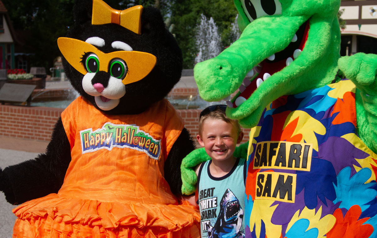 Kitty Claws and Safari Sam hugging a child in front of the Christmas Plaza Fountain