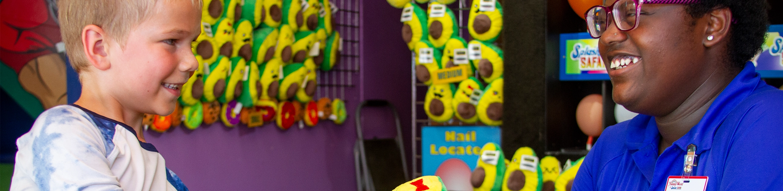 A Team Member smiles with a young boy playing a game at Holiday World.