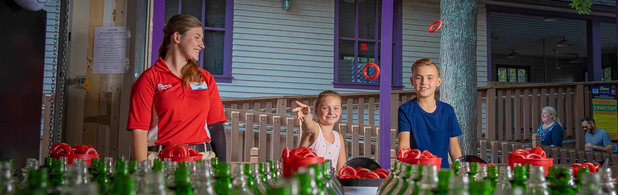 A Team Member watches a young girl try her chances at Raven's Ring Toss at Holiday World.