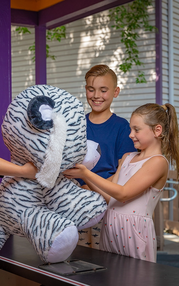 A young boy and girl win a large prize after playing a game at Holiday World.