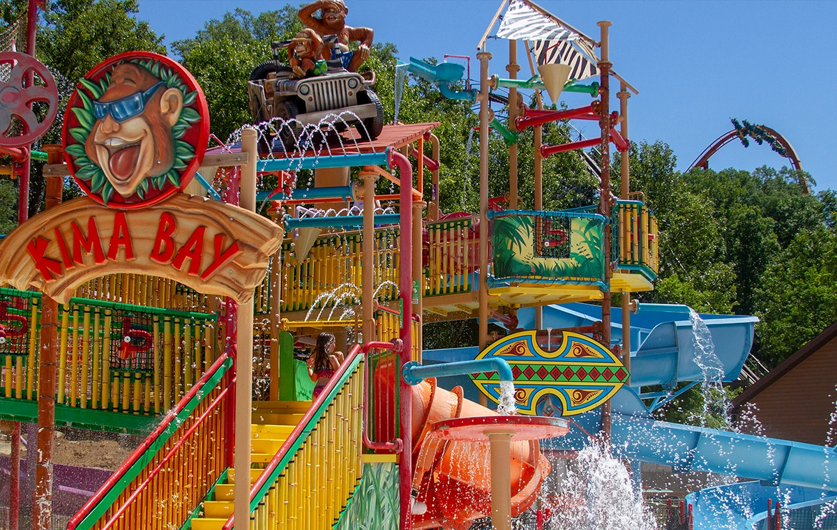 The structure of Kima Bay with Thunderbird peeking over the trees in the background at Holiday World & Splashin' Safari in Santa Claus, Indiana.