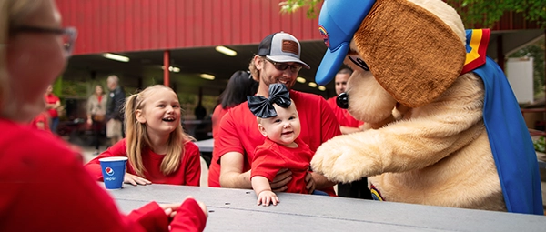 Holidog plays with an infant while their family attends a Group Outing at Holiday World.